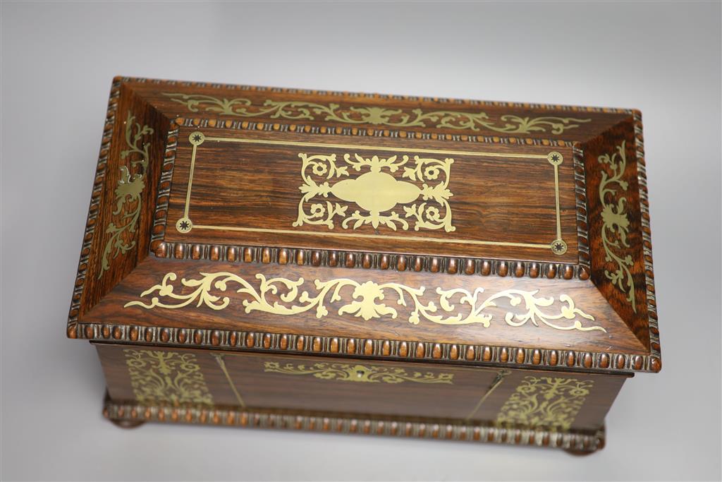 A Regency rosewood and cut brass inlaid sarcophagus shaped tea caddy, (mixing bowl restored), length 33cm